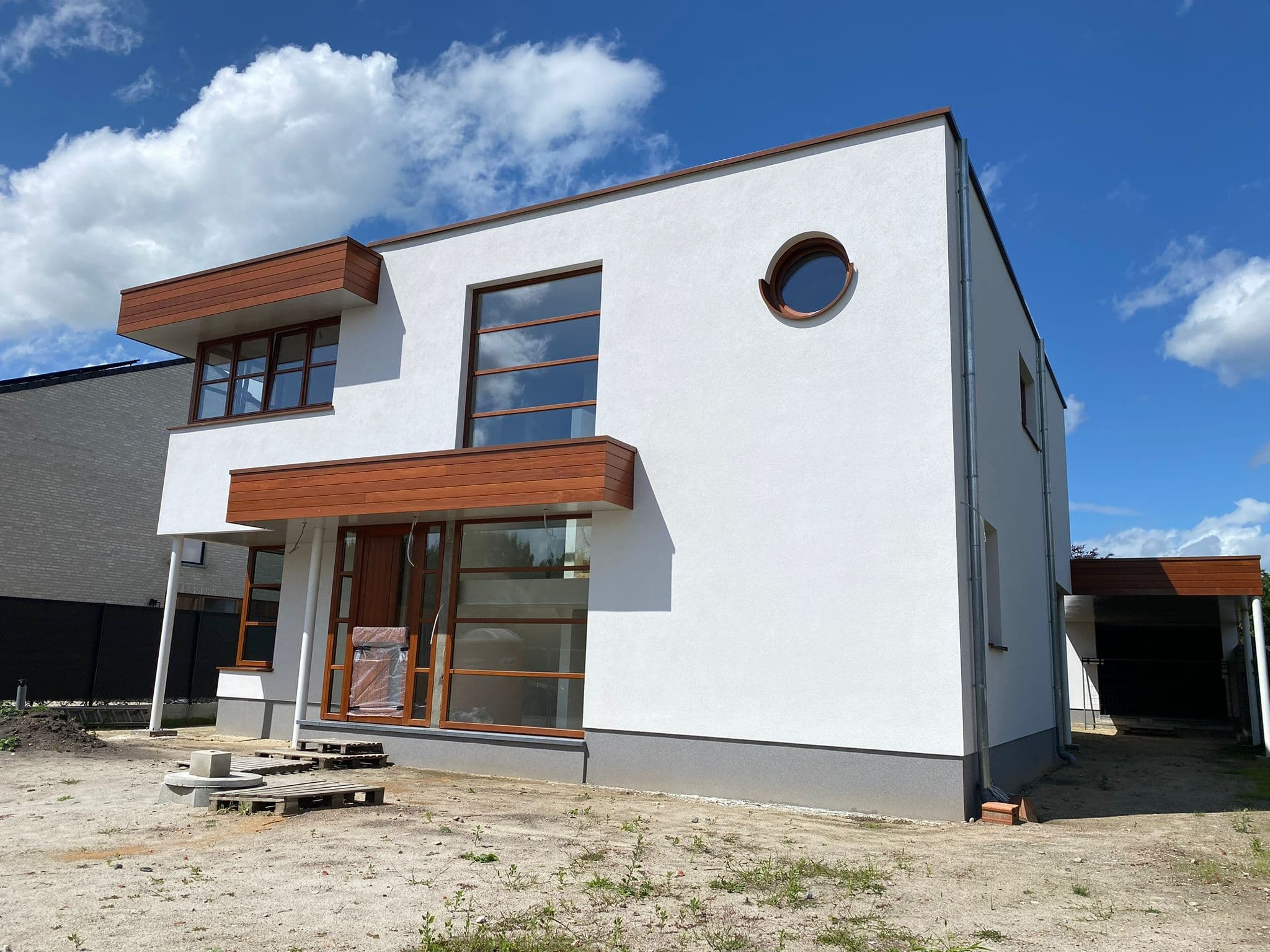 Moderne witte villa met houten accenten en rond raam — Bouwwerken Apers